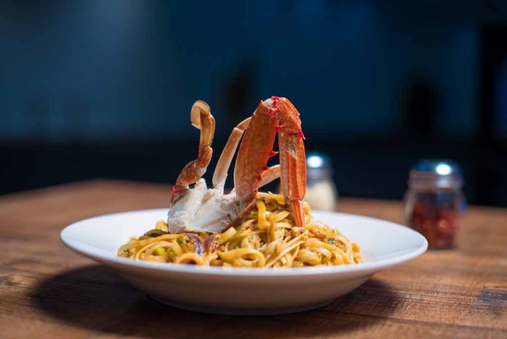 A close-up of a dish of Taglioni pasta with langoustines and a rich bisque sauce.